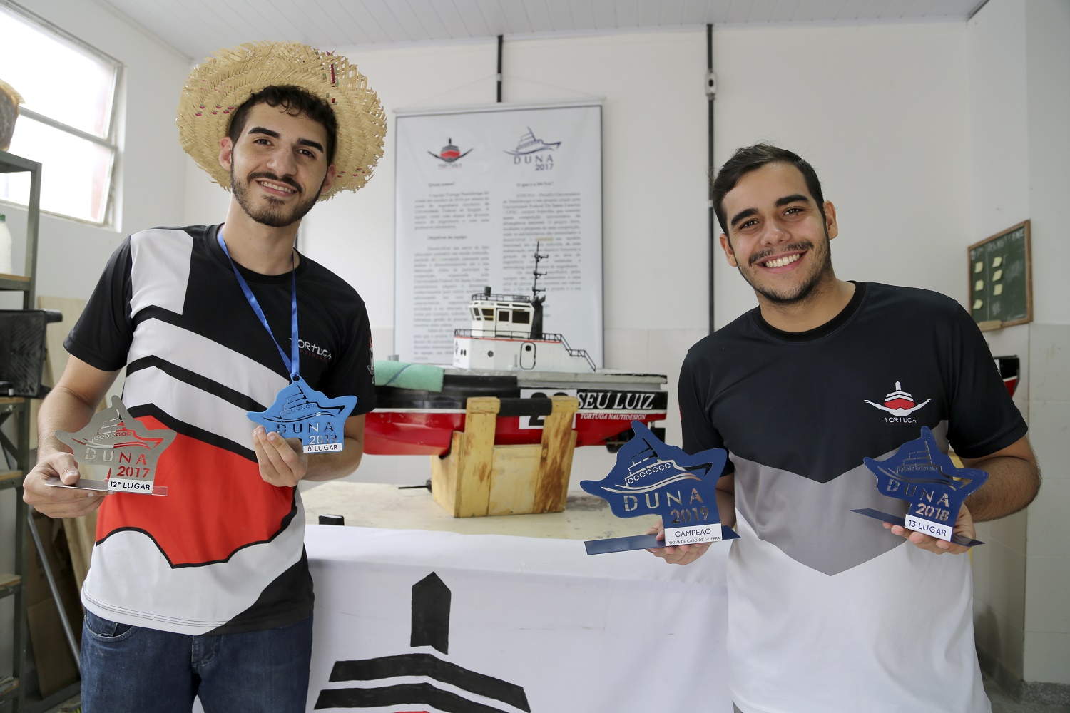 Carlos Eduardo (esq.), capitão da equipe, de Engenharia Mecânica, e Nycollas Vitor, de Engenharia de Petróleo, exibem os troféus do Duna.  (foto: Schirlene Reis/Ascom UFS)